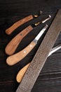 new professional hoof knives with rasp for trimming horsy foot against black wooden background. horse hoof care concept