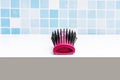 a new purple hairbrush on a white bathroom cabinet and a blue tiled wall in the background