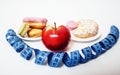 New real diet concept, question sign in shape of measurment tape between red apple and donut isolated on white Royalty Free Stock Photo