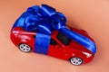 New red car with a blue bow as a gift on a coral background Royalty Free Stock Photo