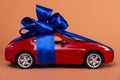 New red car with a blue bow as a gift on a coral background Royalty Free Stock Photo