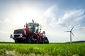 New red modern farm tractor with quad tracks for powerful combine trailer and ploughing trac attachments parked in sunshine.