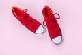 New red sneakers on pink background with copy space.