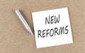 NEW REFORMS text on sticky note on a cork board with pencil