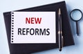 NEW REFORMS - word in notepad on black notepad, magnifying glass and pen background Royalty Free Stock Photo