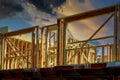 New construction home residential construction home framing against a dramatic sunset sky bright horizon Royalty Free Stock Photo