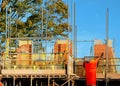 New residential house under construction and scaffolds erected around it to provide safe working platform to brick and other