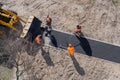 New road construction workers laying asphalt surface on walkway. Hot asphalt paving road workers team. Ground work