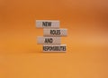New roles and responsibilities symbol. Wooden blocks with words New roles and responsibilities. Beautiful orangebackground. Royalty Free Stock Photo