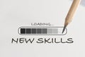 New skills loading written on white paper with processing symbol and pencil Royalty Free Stock Photo