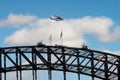 New South Wales Air Ambulance flying over the top of Sydney Harbour Bridge with bridge climbers on top in Sydney, NSW, Australia