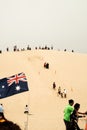 Tourists sliding sand board down the sand dunes in Port Stephen, Australia