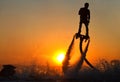 The new spectacular sport, the flyboard is showed in the coast of beach on the sunset. Man on flyboard Royalty Free Stock Photo