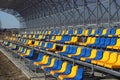 New stands on the football field of metal light construction with plastic seats in blue and yellow. Places for fans in the stadium