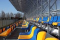 New stands on the football field of metal light construction with plastic seats in blue and yellow. Places for fans in the stadium
