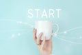 New start, beginning, business concept. Cropped view of female hand with white coffee cup and sign START Icon on blue background Royalty Free Stock Photo