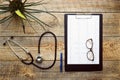 New stethoscope on wooden table with cardiogram isolated