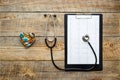 New stethoscope on wooden table with cardiogram and pills