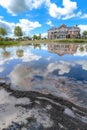 New Suburban Home Construction by Lake with Mud, Reflections of Sky, and Clouds on Water Royalty Free Stock Photo