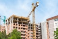 New tall residential building construction site in the city with cranes and scaffolding, blue sky background