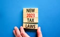 New 2023 tax laws symbol. Concept words New 2023 tax laws on wooden blocks. Beautiful blue table blue background. Businessman hand