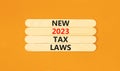 New 2023 tax laws symbol. Concept words New 2023 tax laws on wooden stick. Beautiful orange table orange background. Business new