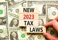 New 2023 tax laws symbol. Concept words New 2023 tax laws on wooden blocks. Beautiful background from dollar bills. Businessman