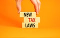 New tax laws symbol. Concept words New tax laws on wooden blocks on a beautiful orange table orange background. Businessman hand. Royalty Free Stock Photo