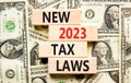 New 2023 tax laws symbol. Concept words New 2023 tax laws on wooden blocks. Dollar bills. Beautiful background from dollar bills.