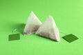 New tea bags with tabs on green background, closeup Royalty Free Stock Photo