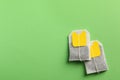 New tea bags with tabs on green background, flat lay. Space for text Royalty Free Stock Photo