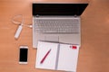 New technology on the desk: open laptop with charging power bank, mobile phone and open empty notebook with red pen and memory Royalty Free Stock Photo