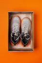 New textile sneakers in the open box over orange background