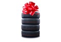 New tires pile as a gift  isolated on white. Tyres pile with a big red bow, as a present or bonus for buying a car Royalty Free Stock Photo