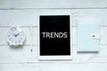 New trends technology business concept. Top view of clock,pen,notebook and tablet written with Trends on white wooden background.