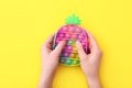 New trendy popular silicone colorful anti stress Pop It toy for child on yellow background. View from above.