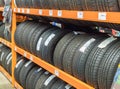 Car tires stacked in rows on shelves or rack in auto store. Variety of car\'s tyres on shelf with prices at store