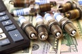 New and used spark plugs on dollar banknotes