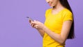 New useful application. Asian girl using cellphone on purple background, empty space