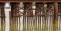 New Westminster, BC. Old wooden train bridge across Fraser River. Reflection of the rustic wooden bridge in the water Royalty Free Stock Photo