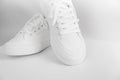 New white female or teen sneakers isolated on white background. White textile sneakers with rubber soles with tied laces on a