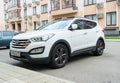 New white Hyundai Santa Fe parked on the street near the house.