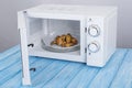 White microwave oven, on a blue wooden surface for heating food Royalty Free Stock Photo