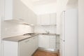 New, white wooden kitchen with gray stone top in renovated interior Royalty Free Stock Photo