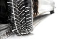 New winter tire in a silver car standing on a snow-covered road in the forest, a visible tread with snow. Royalty Free Stock Photo