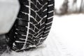 New winter tire in a silver car standing on a snow-covered road in the forest, a visible tread with snow. Royalty Free Stock Photo