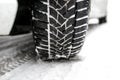 New winter tire in a silver car standing on a snow-covered road in the forest, a visible tread with snow. Royalty Free Stock Photo