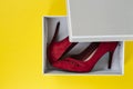 New women`s red suede shoes in a box on a yellow background. Royalty Free Stock Photo