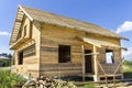 New wooden ecological traditional cottage of natural lumber materials with steep roof under construction in green neighborhood on