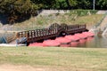 New wooden floating pontoon bridge with strong red floats and center arch secured with wooden fence on calm river Royalty Free Stock Photo